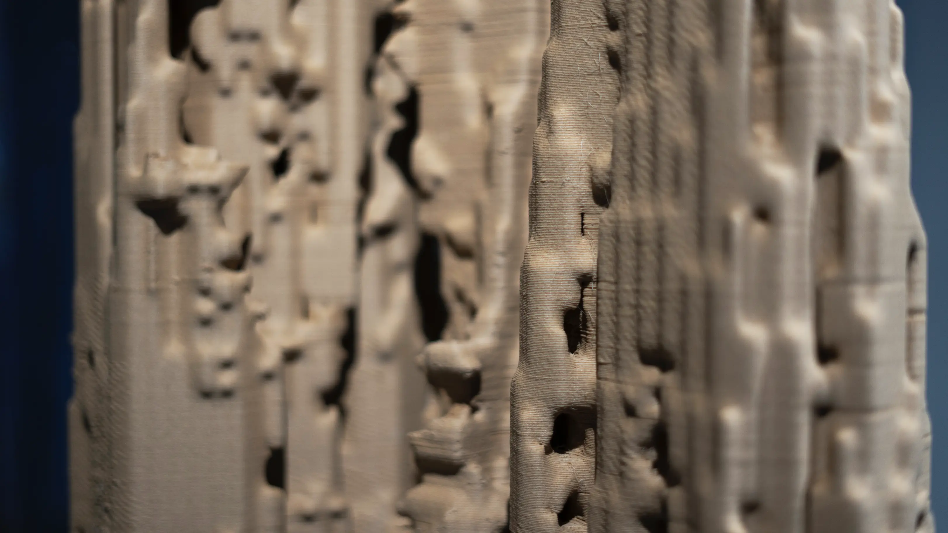 Detail of the ARBOR sculpture's surface, revealing the intricate pattern of 3D-printed layers and voids that mimic natural wood cellular structure.