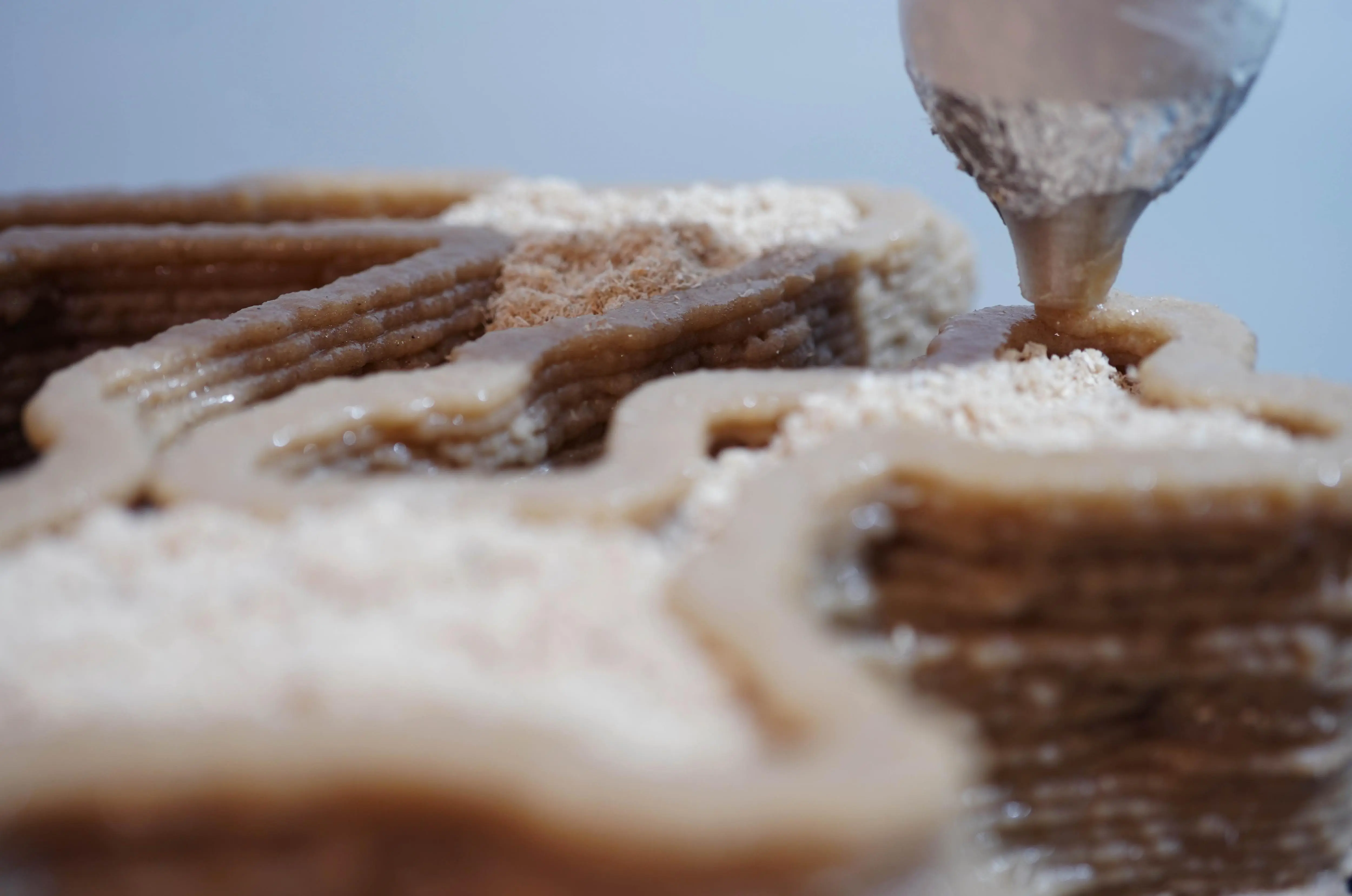 Material exploration: Close-up of wood-based 3D printing material deposition, showing the layered structure and texture of the 40% wood and 60% PLA filament mixture.